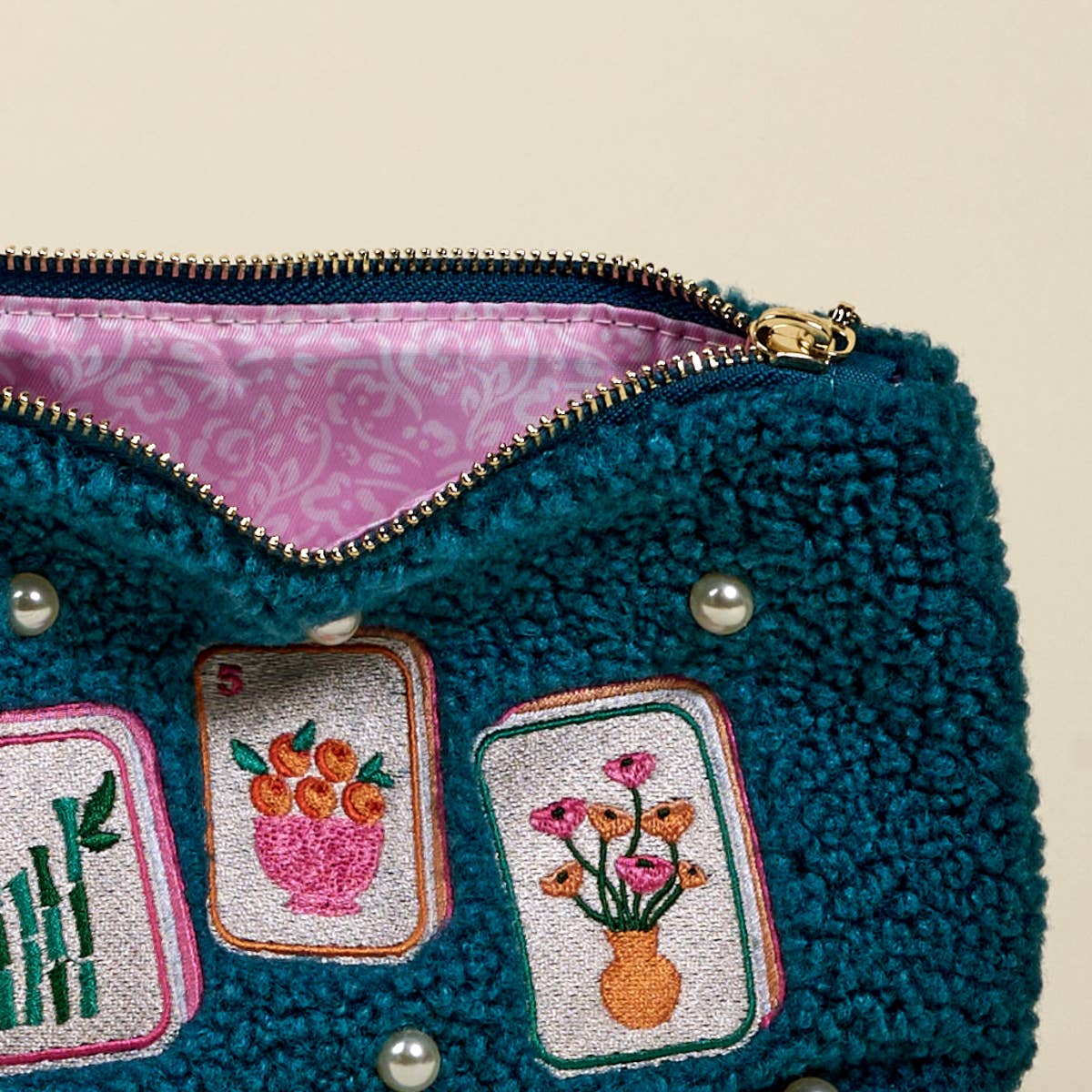 Teal textured pouch with embroidered patches and a pink interior