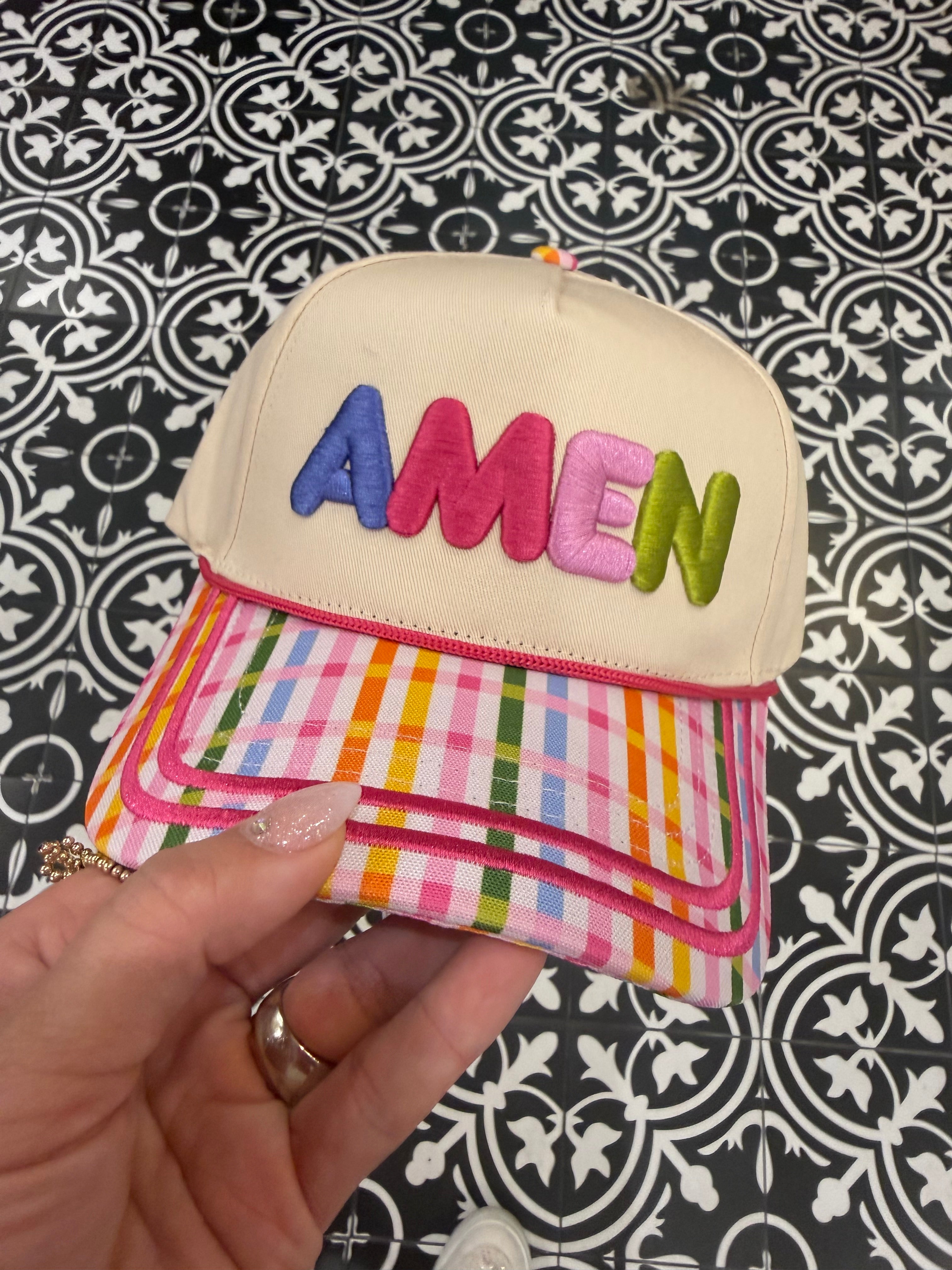 Colorful pouch with 'AMEN branding held by a hand against a patterned background
