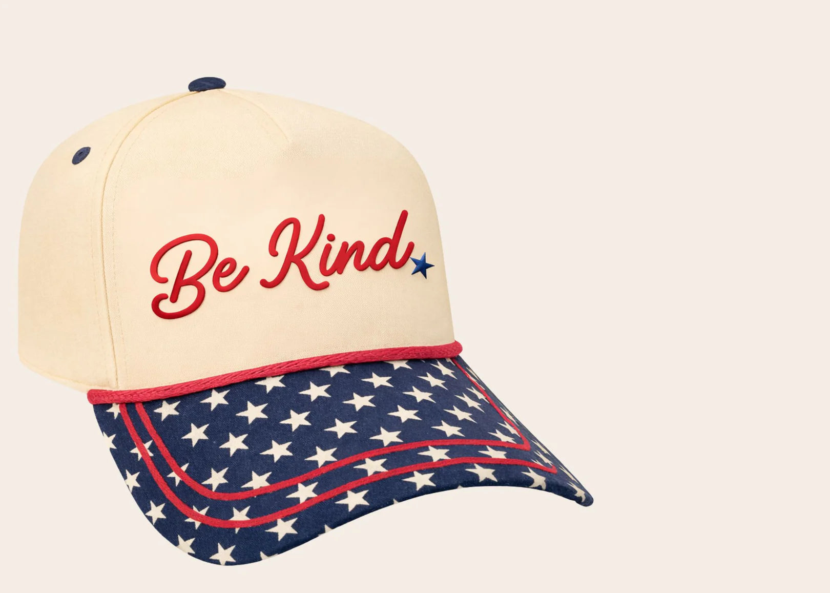 Cap with 'Be Kind' text and American flag pattern on a beige background with stars on the bill