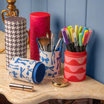 Collection of colorful makeup containers with various cosmetic items on a marble surface.