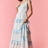 Woman wearing a layered dress with blue accents on a pink background