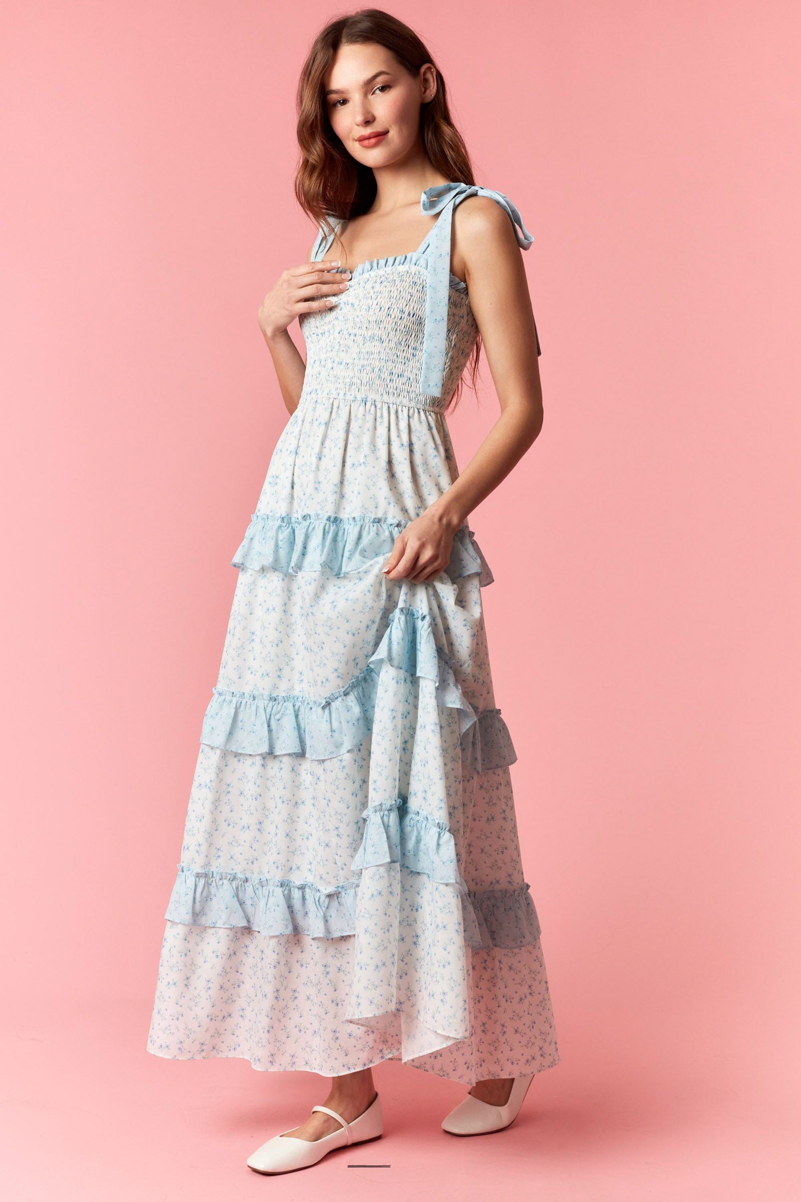 Woman wearing a layered dress with blue accents on a pink background