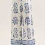 White pants with blue floral patterns worn by a person on a white background