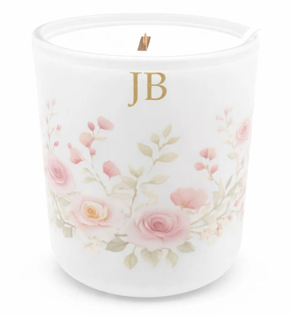 Candle with floral design and initials 'JB' on a white background