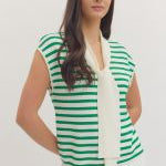 Woman wearing a green and white striped sleeveless top with a plain background