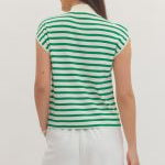 Woman wearing a green and white striped shirt and white pants on a plain background