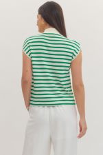 Woman wearing a green and white striped shirt and white pants on a plain background