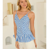 Woman wearing a blue and white striped top with white shorts indoors.