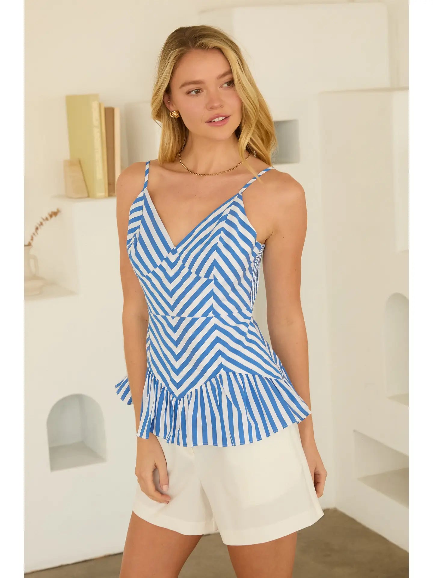 Woman wearing a blue and white striped top with white shorts indoors.