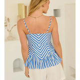 Woman wearing a blue and white striped top and white shorts in a minimal indoor setting.