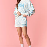 Woman wearing a tie-dye 'USA' outfit on a pink background