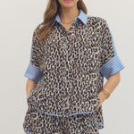 Woman wearing a leopard print outfit with blue accents on a plain background