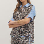 Woman wearing a leopard print dress with blue accents on a plain background