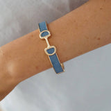 Bracelet with blue strap and gold accents on a wrist against a neutral background