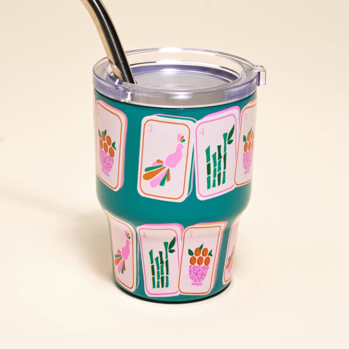 Teal tumbler with colorful designs on a beige background